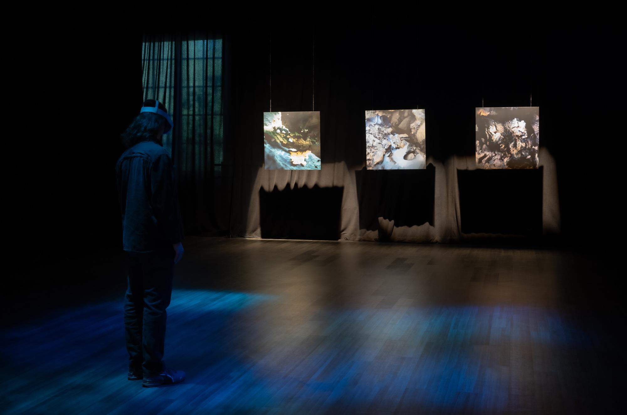 Person standing in a dark room with a virtual reality headset.